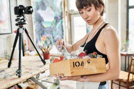Téléchargez les photos : Une femme tenant une boîte remplie de diverses peintures. - en image libre de droit