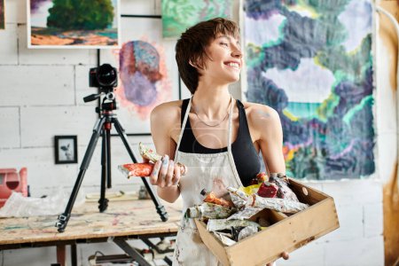 Téléchargez les photos : Une femme tenant une boîte de peinture devant une caméra. - en image libre de droit