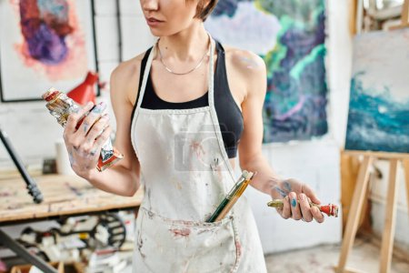 Eine Frau in einem Atelier, die mit dem Pinsel in der Hand malt.