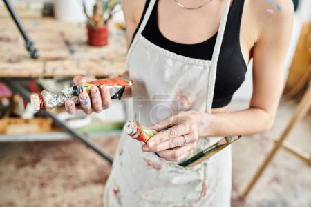Woman wearing apron holding can of paint.