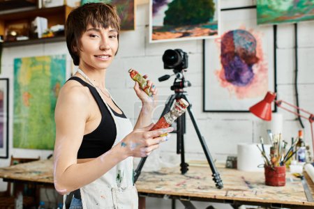 A woman elegantly holding paint in her hand.