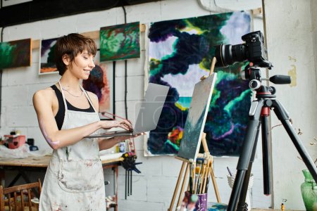Photo for Woman holds laptop in front of painting. - Royalty Free Image