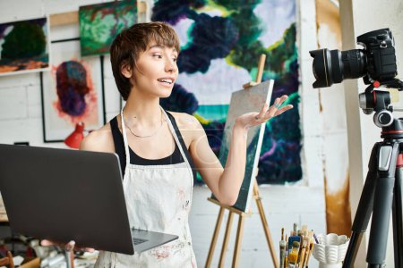 A woman works on a laptop in an art studio.