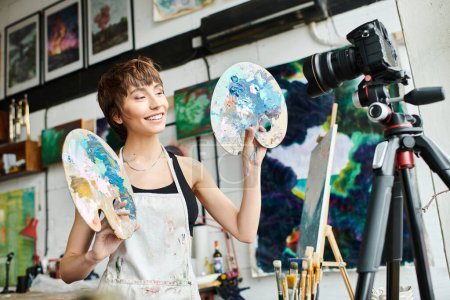 A woman gracefully holds two palettes in front of a camera.