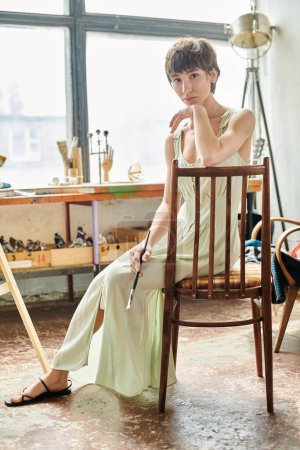 A woman sits gracefully atop a wooden chair.