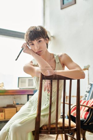 Téléchargez les photos : Femme assise avec un pinceau, perdue dans la pensée. - en image libre de droit