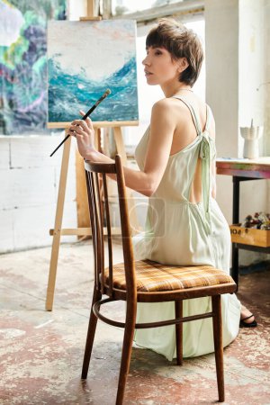Téléchargez les photos : Femme assise sur une chaise, admirant la peinture devant. - en image libre de droit