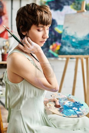 A woman seated, holding a paintbrush.