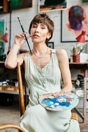 Photo for A woman creates magic with a paintbrush while seated in a chair. - Royalty Free Image