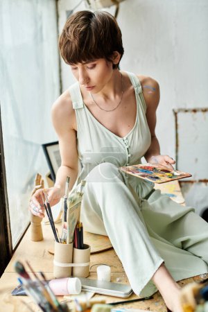 Eine Frau, die auf einem Tisch sitzt und in die Malerei vertieft ist.