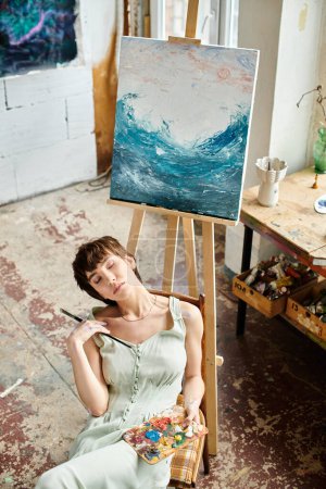Foto de La mujer se sienta delante de la pintura. - Imagen libre de derechos