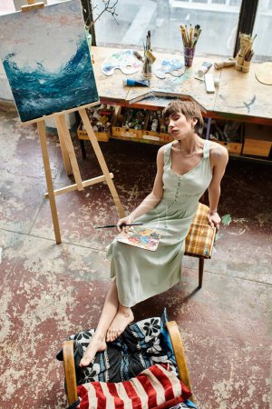 Téléchargez les photos : Une femme s'assoit devant un tableau sur une chaise. - en image libre de droit