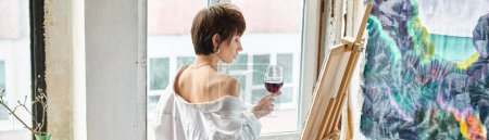 Elegante Frau genießt ein Glas Wein am Fenster.