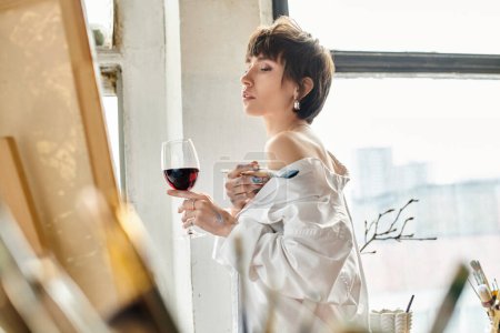 Elegant woman gracefully holds a glass of red wine.