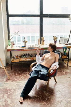 A woman sits on a chair in art studio.