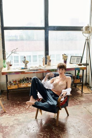 Appealing woman sits on a chair in art studio.