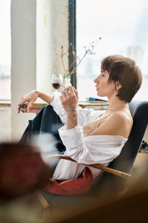 Eine Frau im Stuhl bei einem Glas Wein und einer Zigarette.