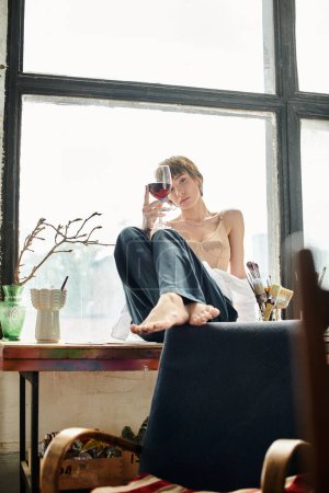 Woman on window sill gracefully holds wine glass.
