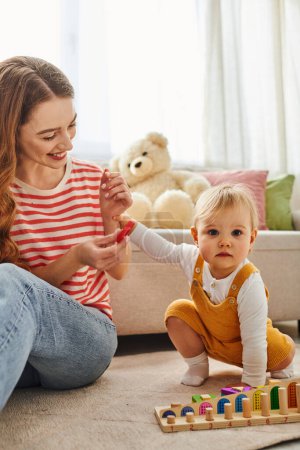 Eine junge Mutter interagiert freudig mit ihrer kleinen Tochter, während sie zu Hause gemeinsam auf dem Boden spielt.