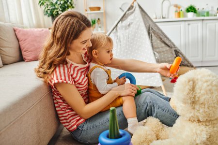 Photo for A young mother and her toddler daughter happily playing together with a teddy bear, creating joyful memories at home. - Royalty Free Image