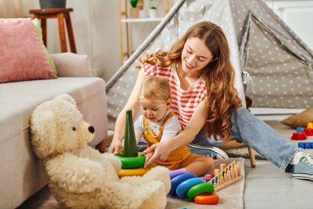 A young mother and her toddler daughter play with colorful toys, bonding and creating memories at home.
