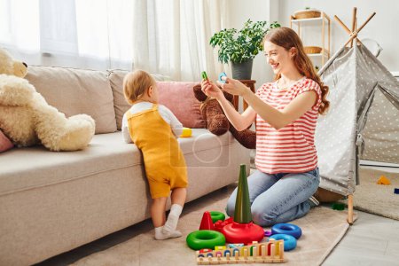 Eine junge Mutter und ihre kleine Tochter lachen und spielen in einem warmen und einladenden Wohnzimmer.