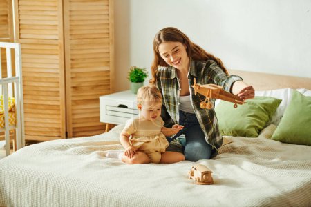 A young mother cherishes quality time with her toddler daughter as they play together on a bed.
