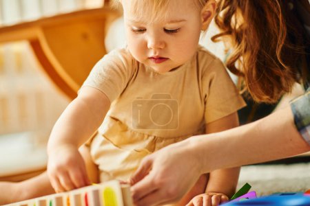 Photo for A young mother and her toddler daughter happily playing together, building structures with colorful blocks. - Royalty Free Image