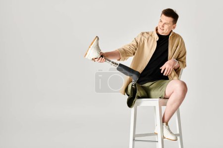 A handsome man with a prosthetic leg sitting on a stool.