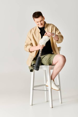 Homme attrayant avec une jambe prothétique assise sur un tabouret.