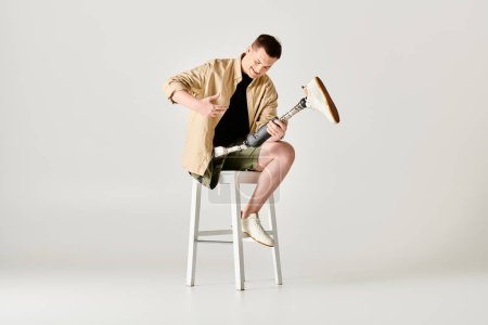 Beau homme avec la jambe prothétique pose activement tout en étant assis sur un tabouret.