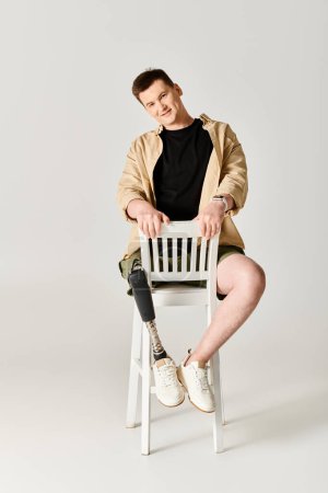 A handsome man with a prosthetic leg sits proudly atop a white chair.