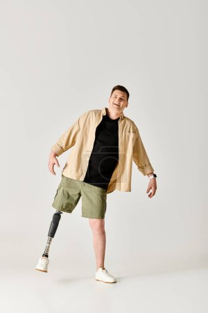 Un bel homme avec une jambe prothétique posant activement dans une chemise noire et un short vert.