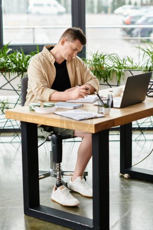 Ein gutaussehender Geschäftsmann mit Beinprothese arbeitet an einem Laptop am Tisch.