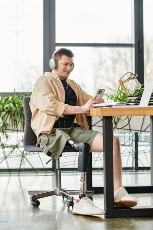 Foto de Un hombre de negocios con una pierna protésica se sienta en una mesa, enfocándose intensamente en la pantalla de su computadora portátil. - Imagen libre de derechos