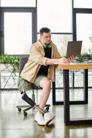 A businessman with a prosthetic leg concentrates while using a laptop at a table.