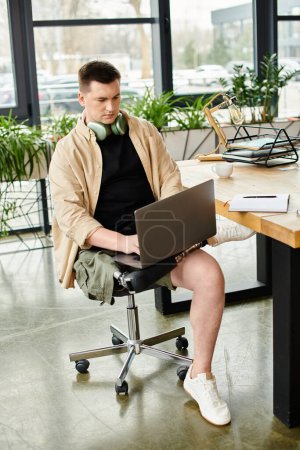 A handsome businessman with a prosthetic leg, engrossed in working on his laptop in an office chair.