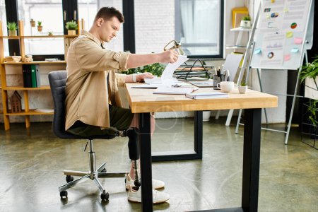 Téléchargez les photos : Un bel homme d'affaires avec une prothèse de jambe travaillant avec diligence à son bureau. - en image libre de droit