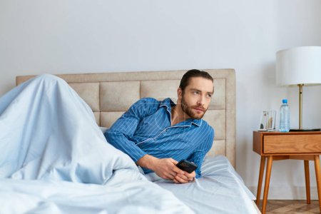 Téléchargez les photos : Un homme allongé paisiblement sur un lit, couvert d'une couverture chaude. - en image libre de droit