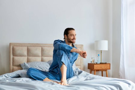 Téléchargez les photos : Un homme en pyjama s'assoit paisiblement sur un lit. - en image libre de droit
