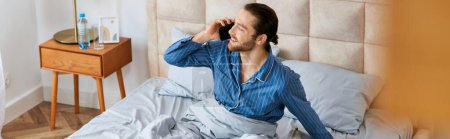 Ein Mann sitzt auf einem Bett und plaudert mit einem Handy.