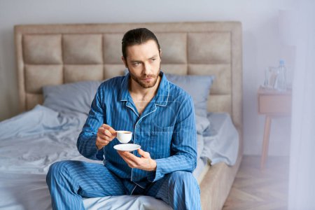 Man enjoys coffee on bed.