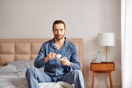 A man in serene morning setting enjoying a cup of coffee on a bed.