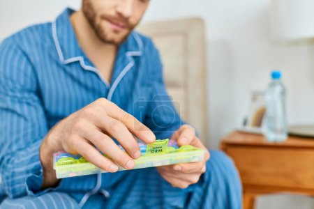 Man sitting on bed, peacefully holding holding pill case.
