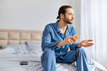 A man peacefully sits on a bed, holding an taking pills in a meditative posture.