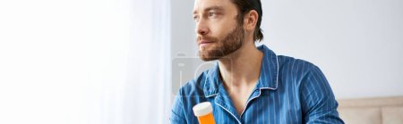 Photo for Handsome man in blue shirt holding bottle of pills. - Royalty Free Image