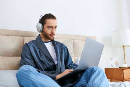 Ein Mann meditiert auf einem Bett, surft auf einem Laptop im Internet.