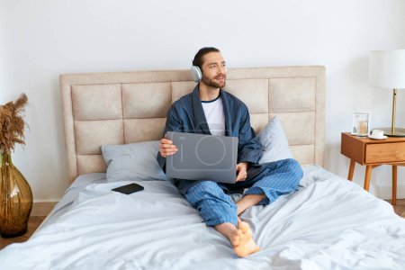 Photo for A man using a laptop on a bed. - Royalty Free Image
