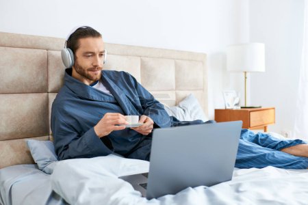 Téléchargez les photos : Un homme en posture de relaxation au lit, à l'aide d'un ordinateur portable. - en image libre de droit
