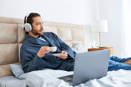 Photo for A man relaxes on a bed with a laptop and headphones, embodying peace and focus. - Royalty Free Image